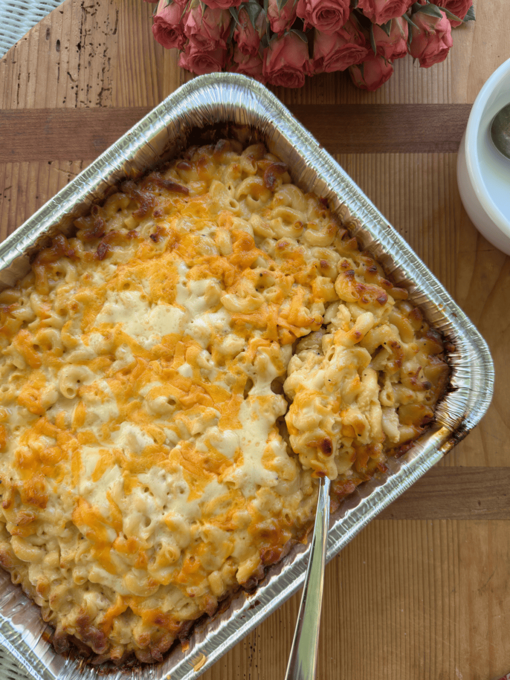 large pan full of creamy mac and cheese with spoon scooping out heaping portion, melty cheese