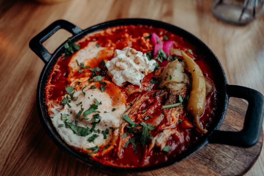 traditional shakshuka dish in cast-iron pan on rustic wooden table