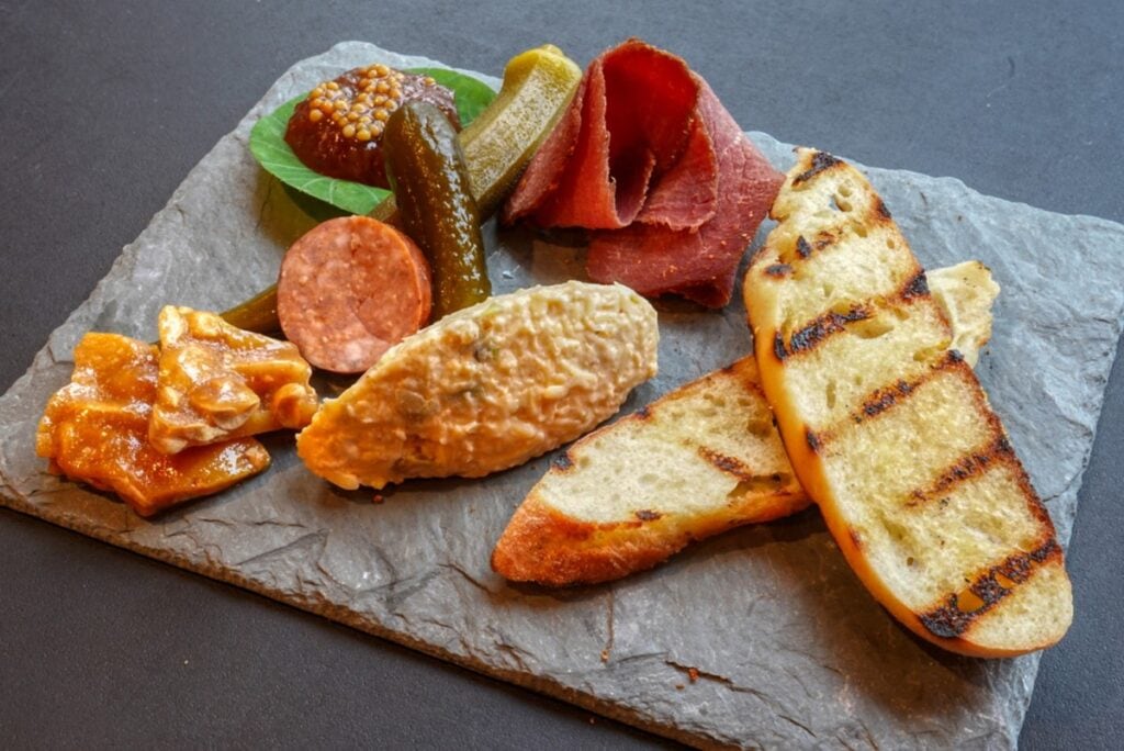 charcuterie board with bread, pastrami, dip, and other appetizers