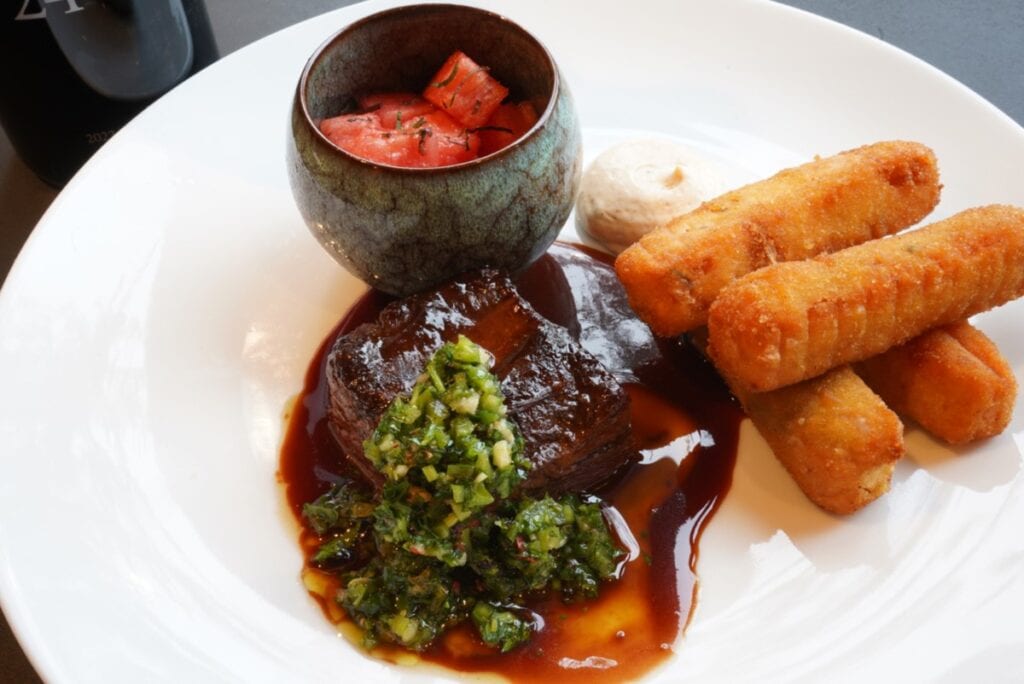 plated short ribs with sauce and sides on white plate
