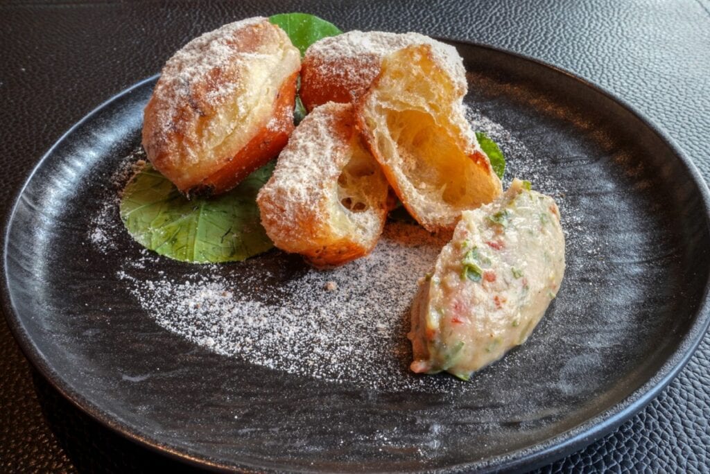 black plate of Dungeness Crab Beignet as first course at Alaskan lodge fine dining
