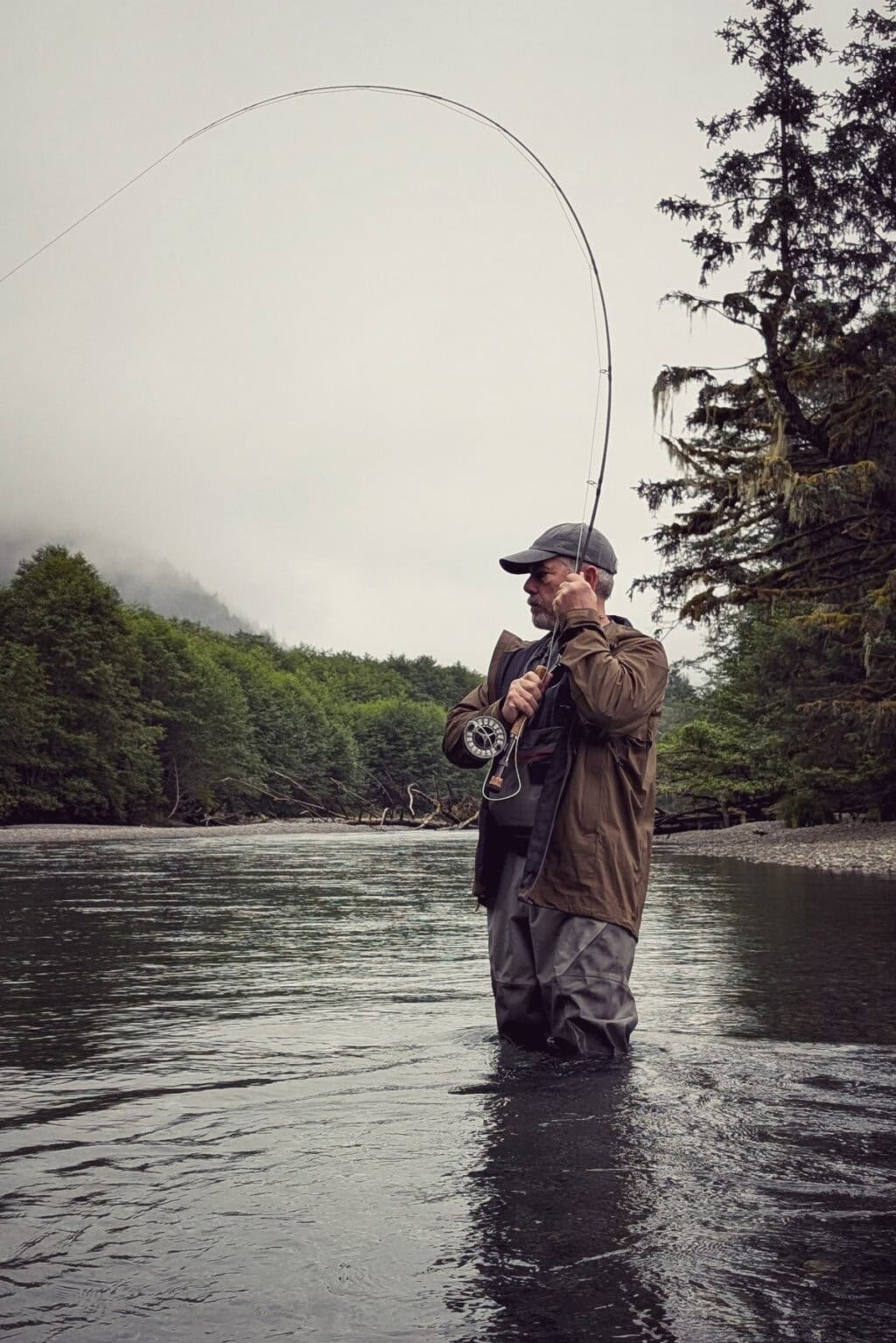 Scott catching a fish while fly fishing in river in Alaska