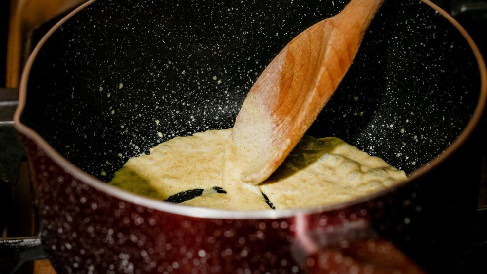 golden roux being stirred in pot with a wooden spoon
