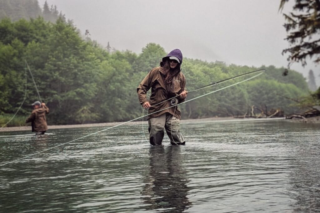 stacy lyn pulling a fish in, fly fishing in Alaskan river