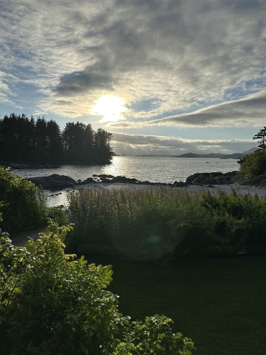 breathtaking sunrise over river near Sitka, Alaska with greenery in foreground and trees, dramatic clouds in distance
