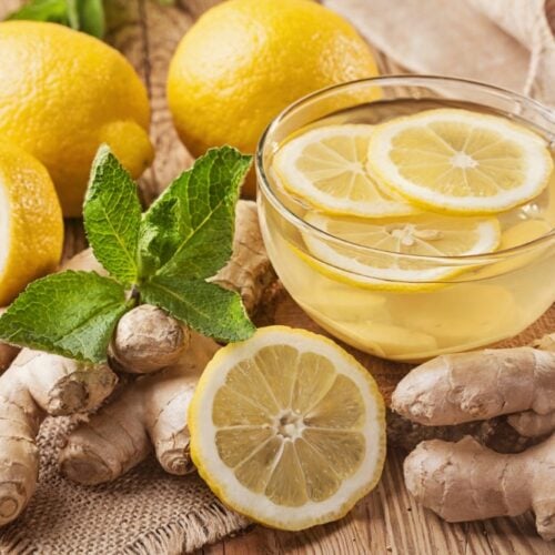 lemon-ginger tea on a wooden table with fresh cut lemons and ginger