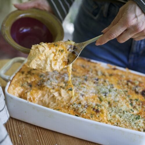 Stacy Lyn spooning creamy buffalo chicken dip from casserole pan into dish