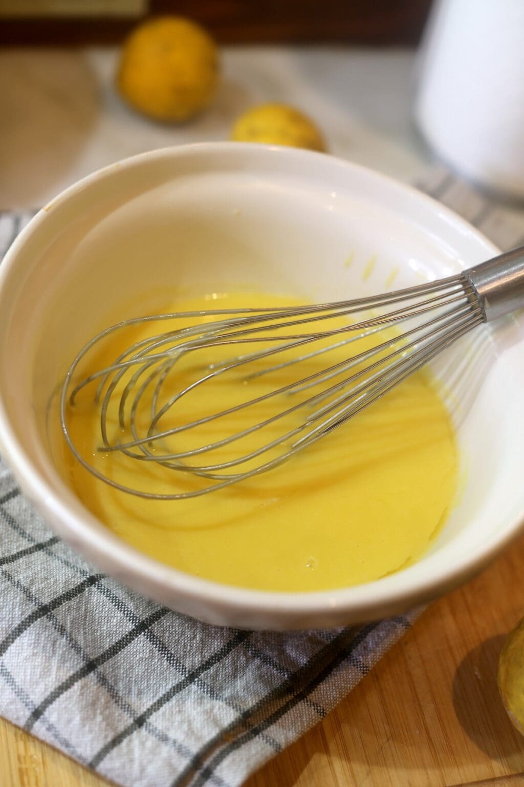 lemon curd preparation - bright yellow egg and lemon mixture with whisk in bowl