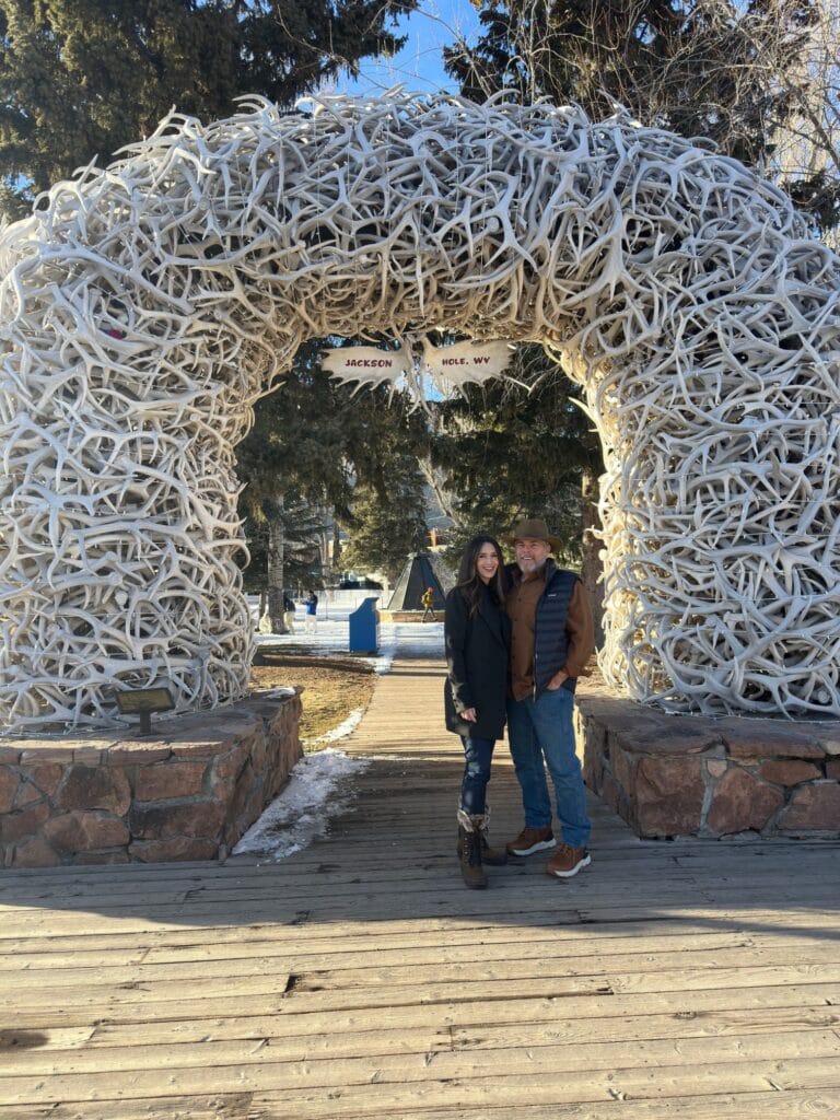 Stacy Lyn and Scott Harris under elk antler arch in Jackson Hole, Wyoming