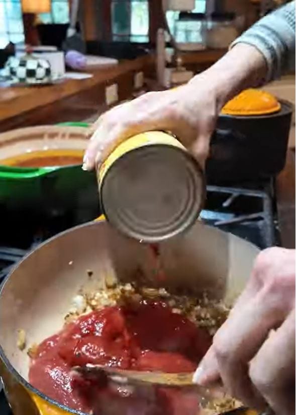 adding canned tomatoes to the Dutch oven