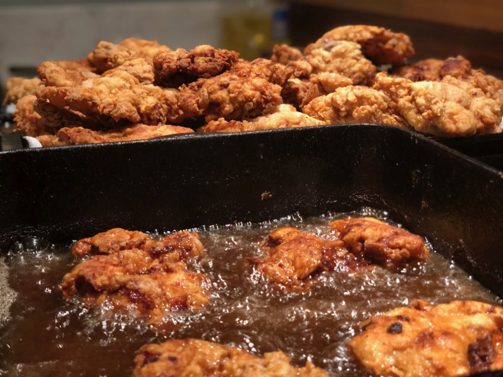 frying up country fried steak in oil with batch already fried in background