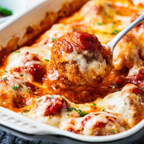 baked cheesy meatball casserole hot from the oven with spoon lifting a meatball