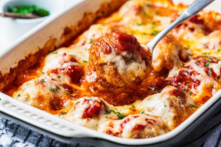 baked cheesy meatball casserole hot from the oven with spoon lifting a meatball