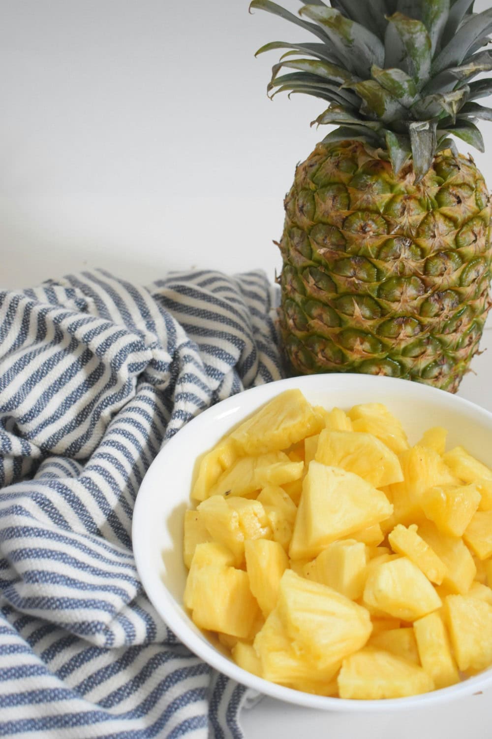 pineapple chunks in white bowl on blue napkin