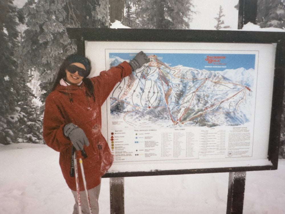 Stacy Lyn on honeymoon in red jacket, pointing at sign