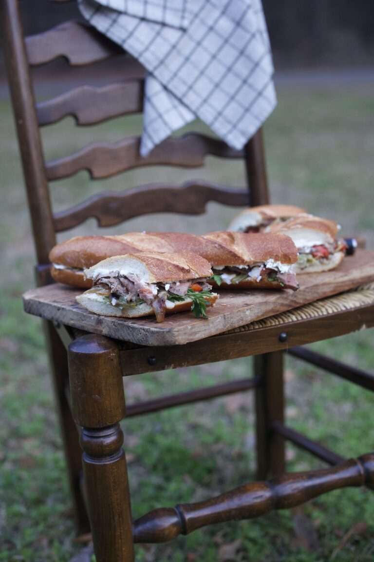 venison steak sandwich - sub length - sliced and set on rustic cutting board on chair outdoors