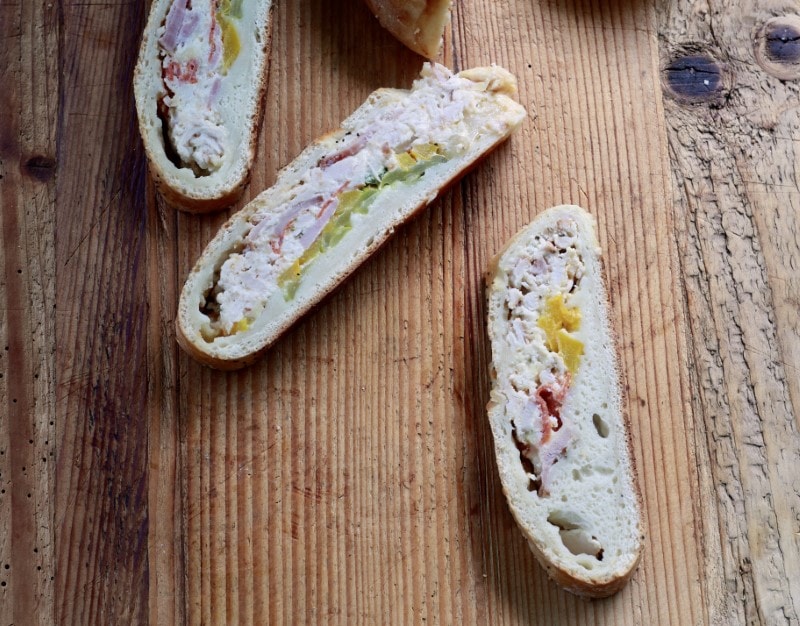 slices of picnic sandwich, inspired by stromboli and calzone recipes, on wood table