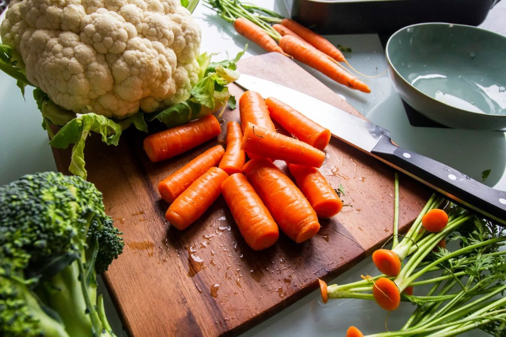 fresh carrots, broccoli, cauliflower on cutting board for vegetable soup