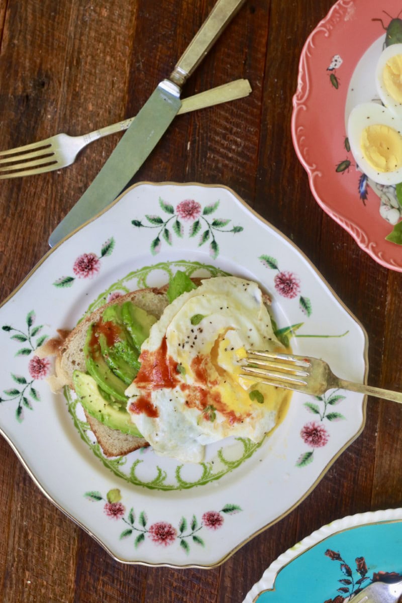 fried eggs on white plate with floral design, fork resting on eggs