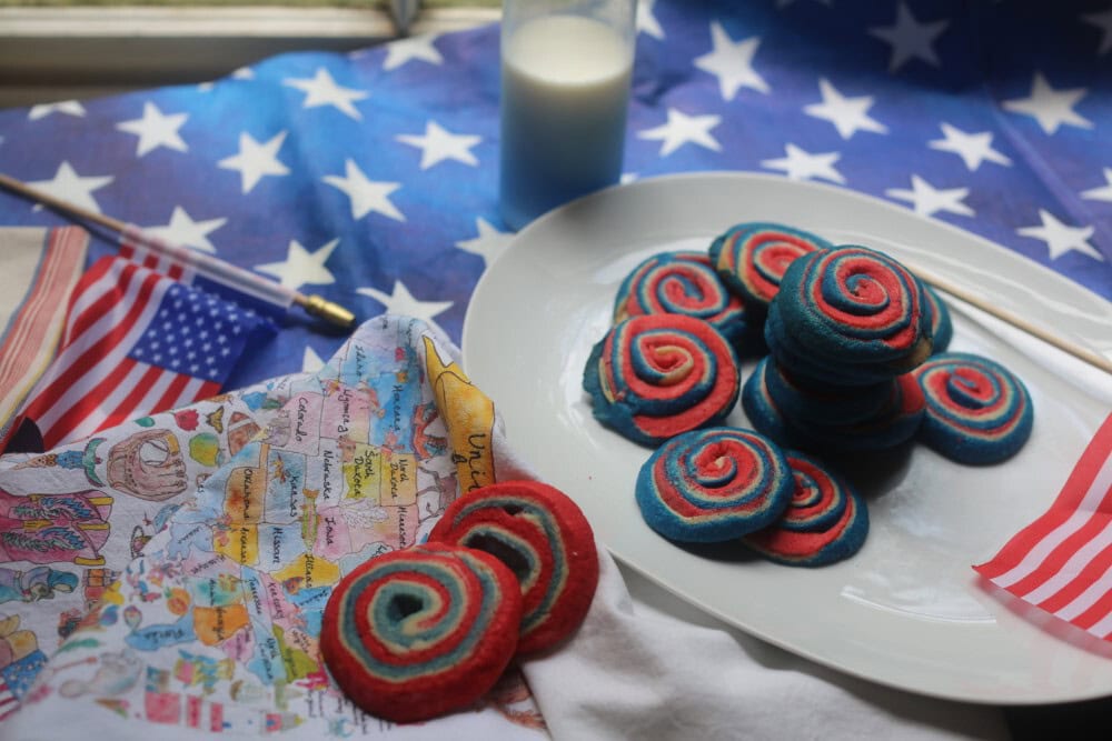Colorful red, white, and blue 4th of July pinwheel cookies on a patriotic tablecloth for Independence Day
