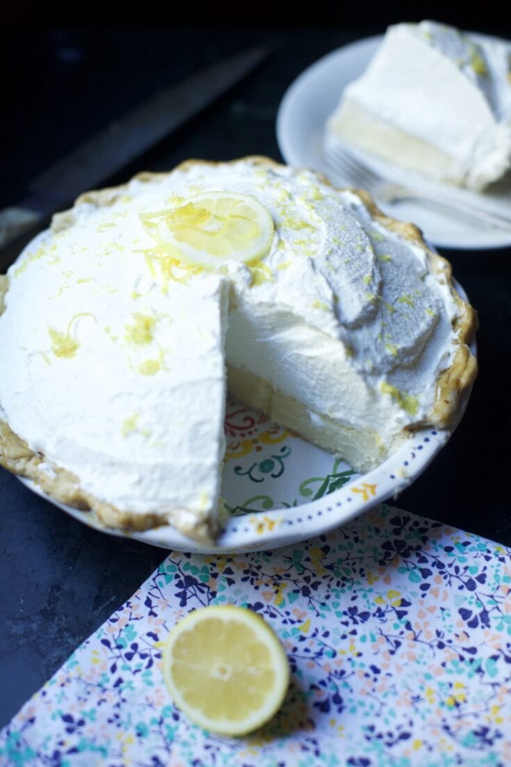 Stacy Lyn's lemon icebox pie with a slice cut out and served on a plate - blue floral napkin in foreground