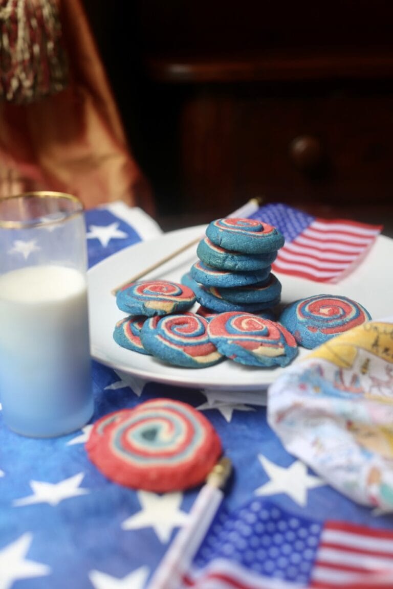 Colorful patriotic 4th of July pinwheel cookies with glass of milk on American flag tablecloth