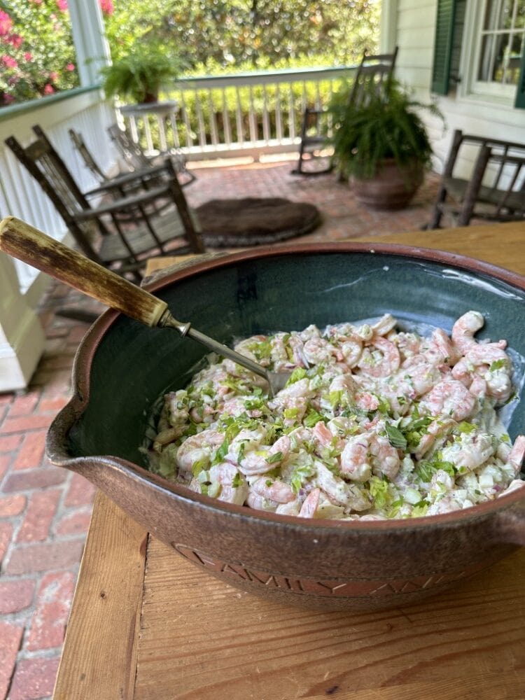 big bowl of shrimp salad with serving spoon on rustic wood porch table