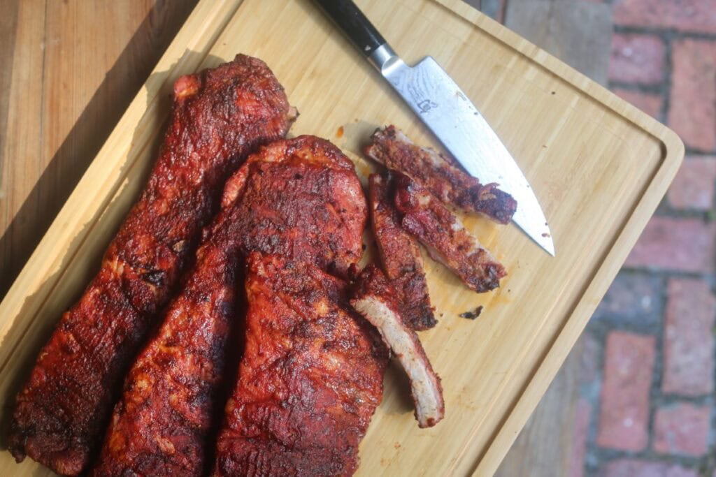 tender BBQ smoked ribs on cutting board outdoors with knife