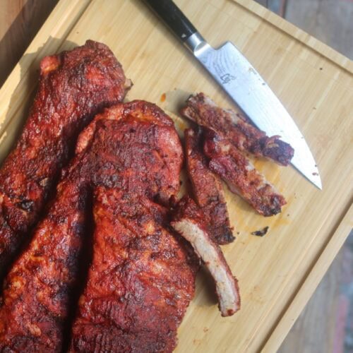 tender BBQ smoked ribs on cutting board outdoors with knife