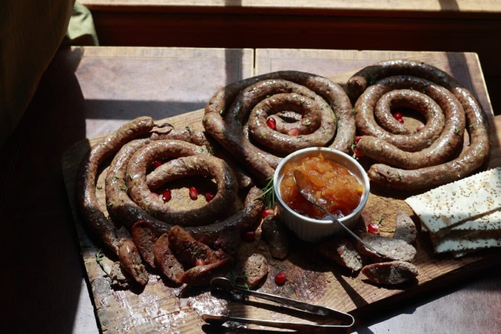 homemade pork sausage links on cutting board with jam and crackers