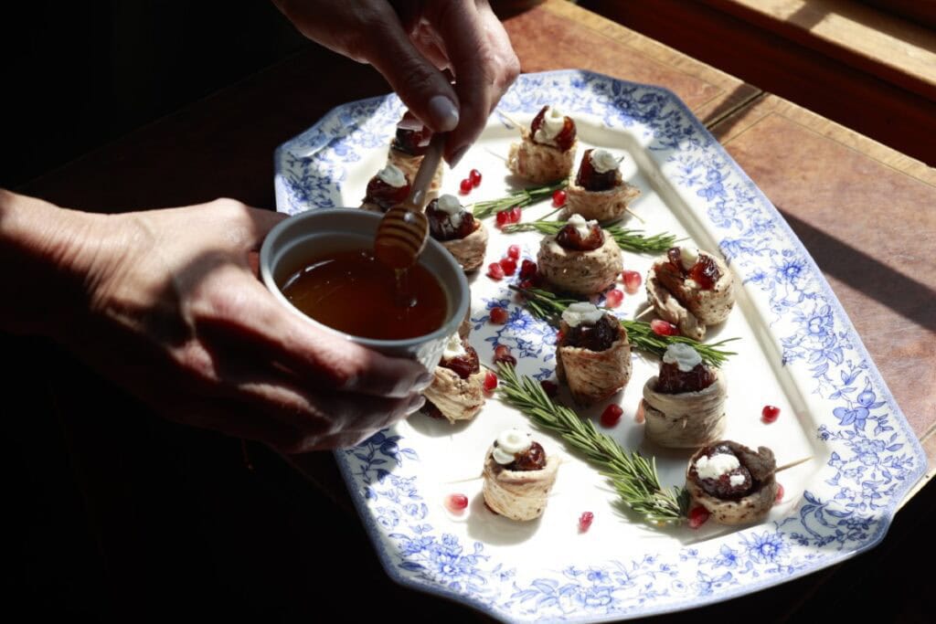 wild turkey breast roll ups on a blue and white china platter, garnished with rosemary - Stacy Lyn is drizzling honey on them