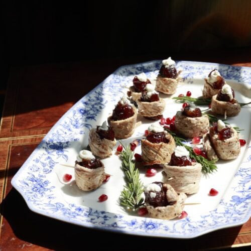 attractively arranged china platter of turkey roll ups with dates and goat cheese